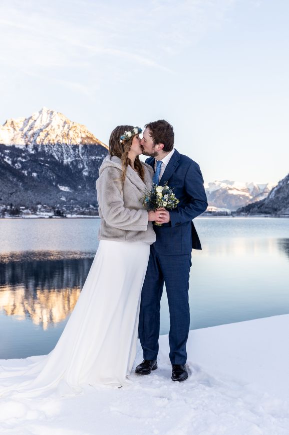 Hochzeit am Achensee, Braut und Bräutigam im Schnee beim Küssen